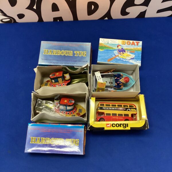 Vintage tin toy boats and Corgi bus in a collectible lot.