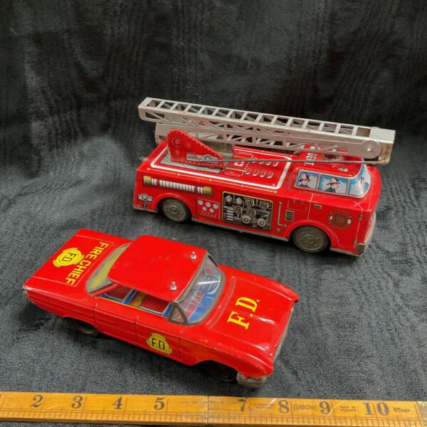 Group of vintage tinplate fire vehicles, including a fire engine and car.
