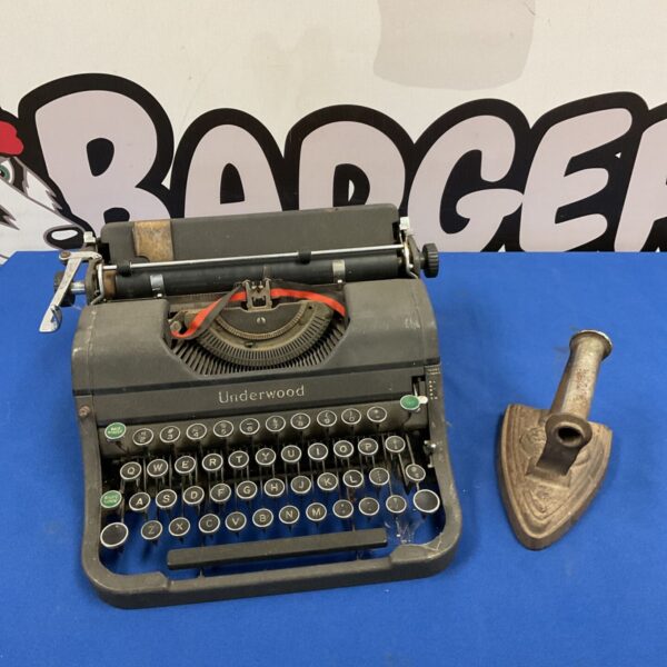 Vintage Underwood mechanical typewriter beside a cast iron flat iron on blue surface