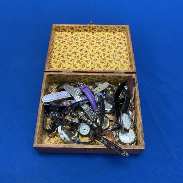 Vintage watch lot displayed inside a floral-lined wooden box.