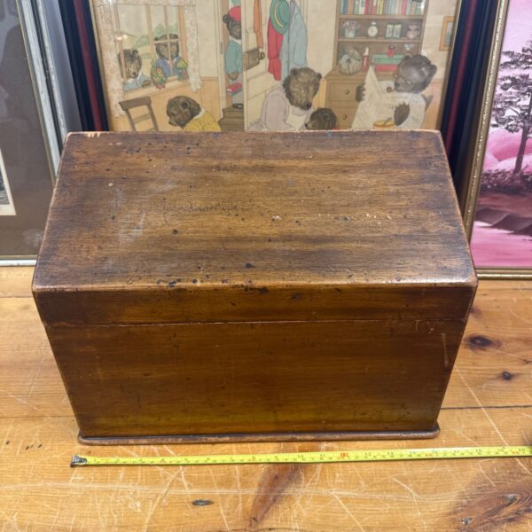 Vintage wooden storage box with artwork in the background.