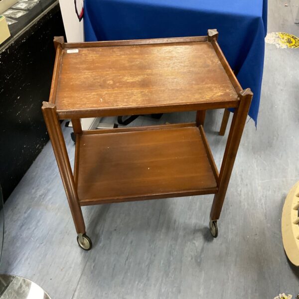 Vintage wooden tea trolley with two tiers and wheels.