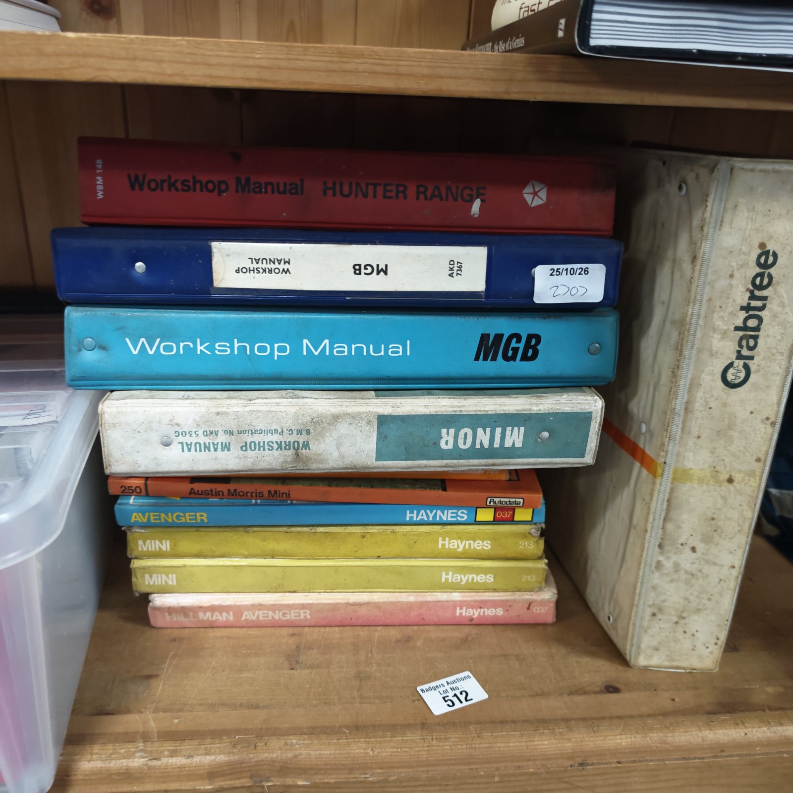 Stack of vintage MGB, Mini, Avenger and Haynes workshop manuals on a wooden shelf