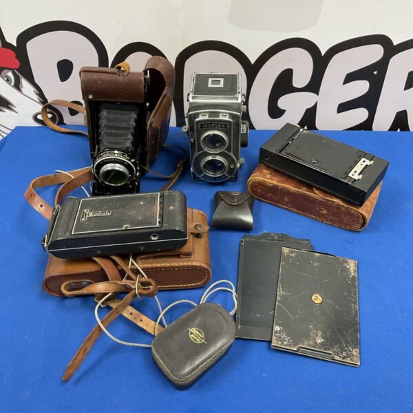 Vintage Zeiss Ikon Ikoflex and Kodak folding cameras with leather cases on a blue table