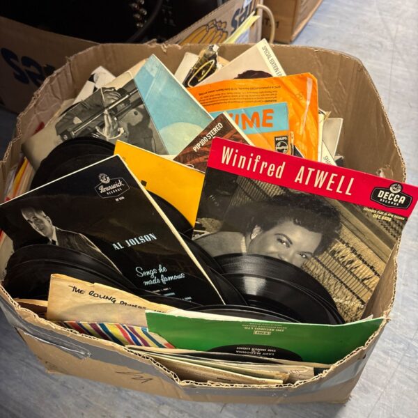 Mixed lot of vintage 7 inch vinyl records in a cardboard box.