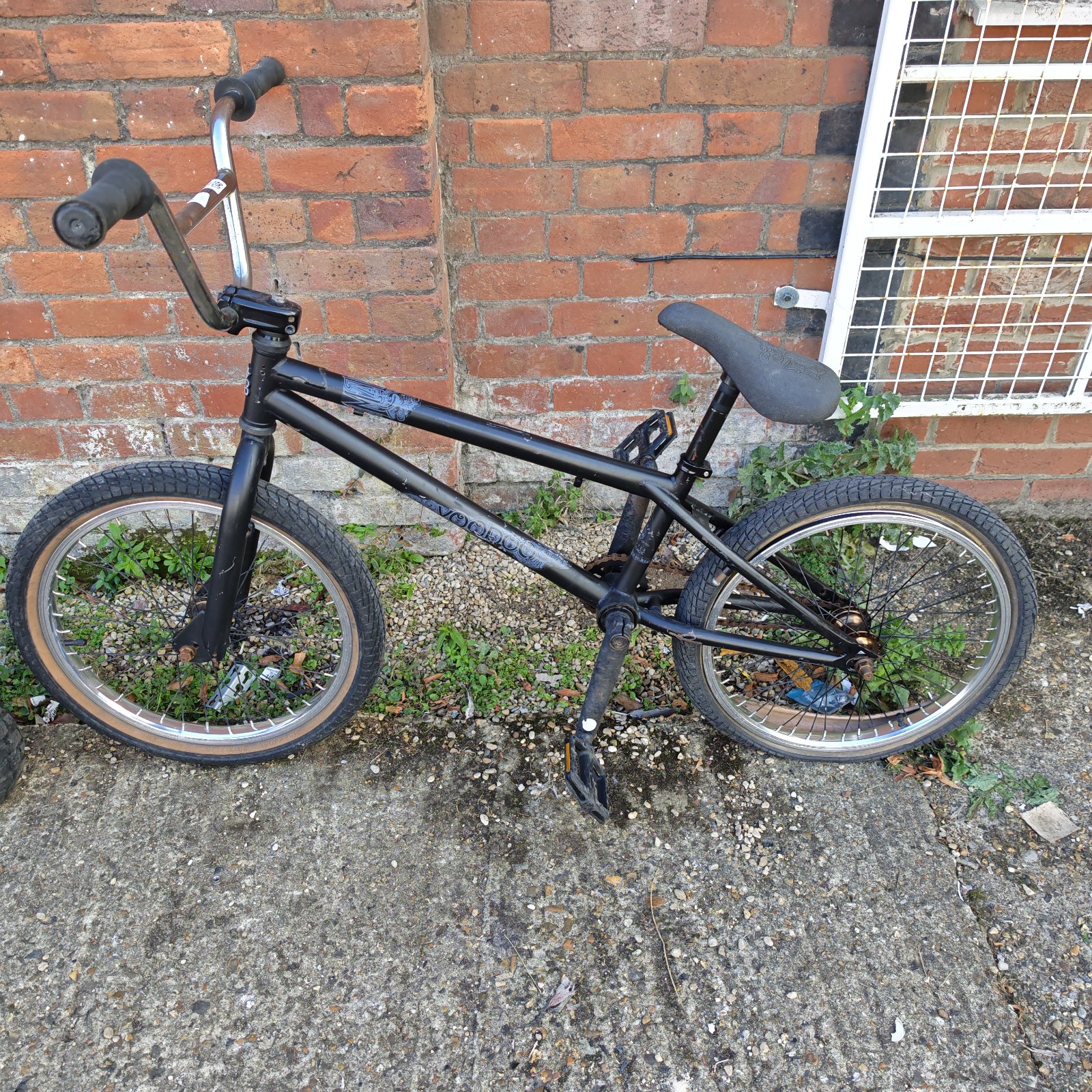 Black Voodoo BMX bike with worn tires and a padded seat.