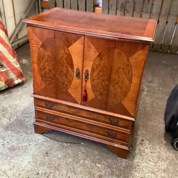 Front view of a brown walnut media unit with burlwood detailing.