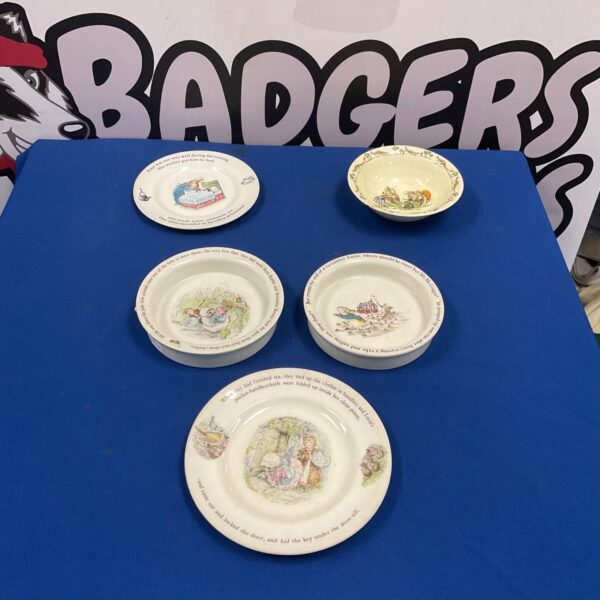 Vintage Wedgwood Beatrix Potter plates and bowls displayed on a blue table