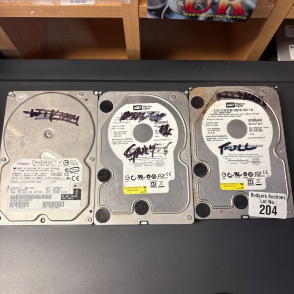 Three hard drives from Western Digital and Hitachi on a desk surface