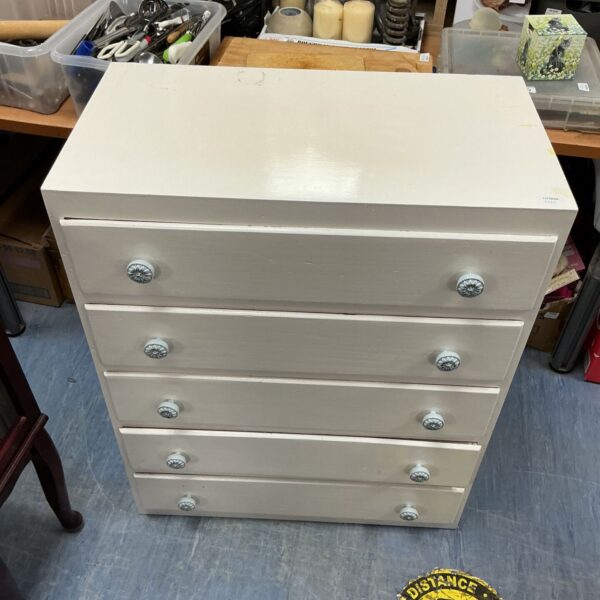 White five-drawer chest of drawers with visible wear.