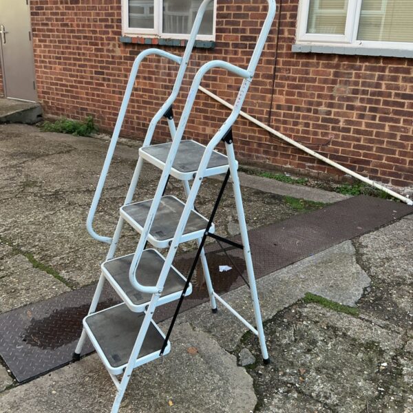 White aluminium step ladder with four treads and curved handrails on a paved surface
