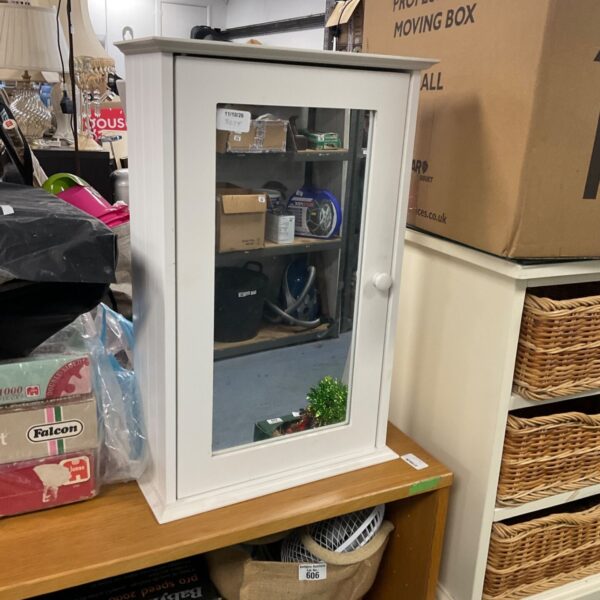 White bathroom mirror cabinet with a mirrored door, showing signs of wear.