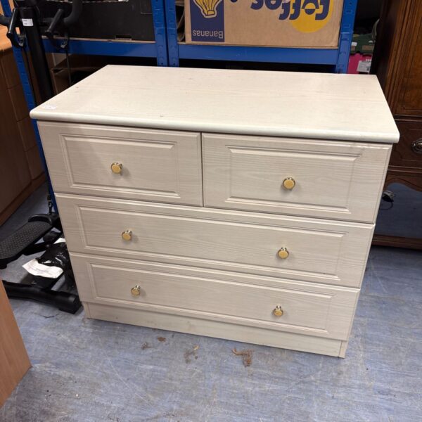 White chest of drawers for bedroom storage, showing signs of wear.