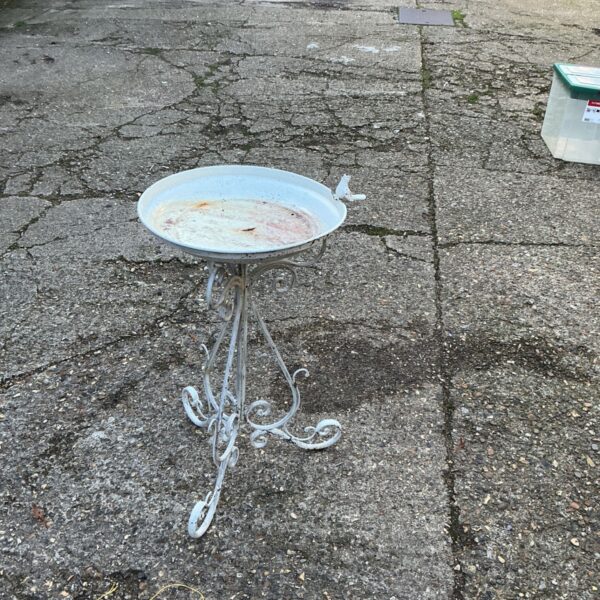 White painted metal bird bath with scrolled stand and bird attached