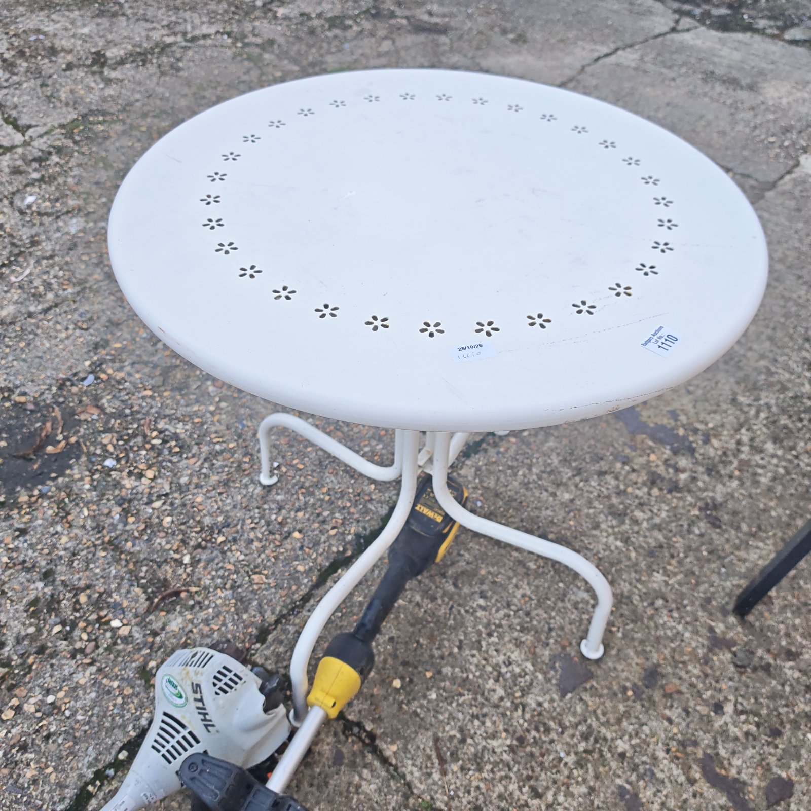 White metal garden table with perforated floral pattern on round top