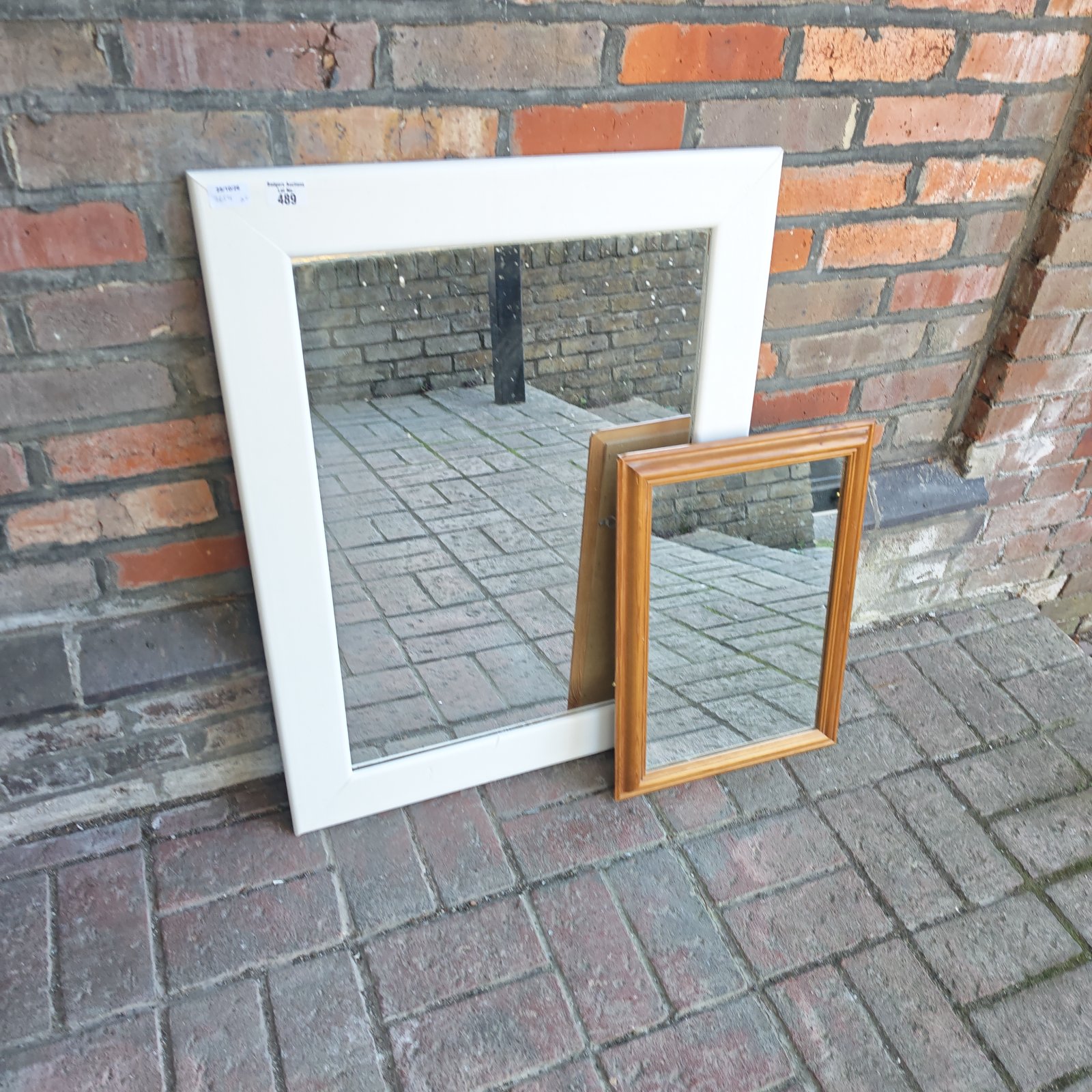 White painted wooden framed mirror beside a smaller wood framed mirror
