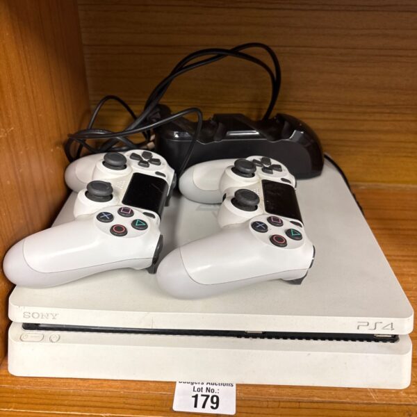 White PlayStation 4 console with two DualShock 4 controllers and docking station.