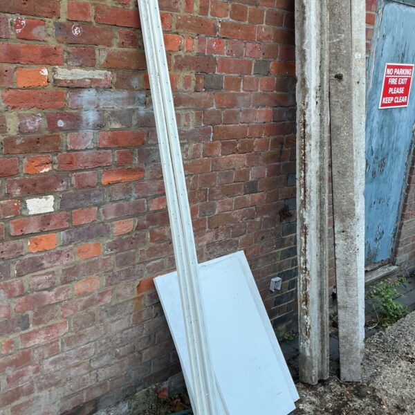 White wall mounted shelf unit components with rails and flat panels leaning against brick wall
