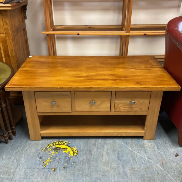 Light wooden coffee table with three drawers and an open lower shelf