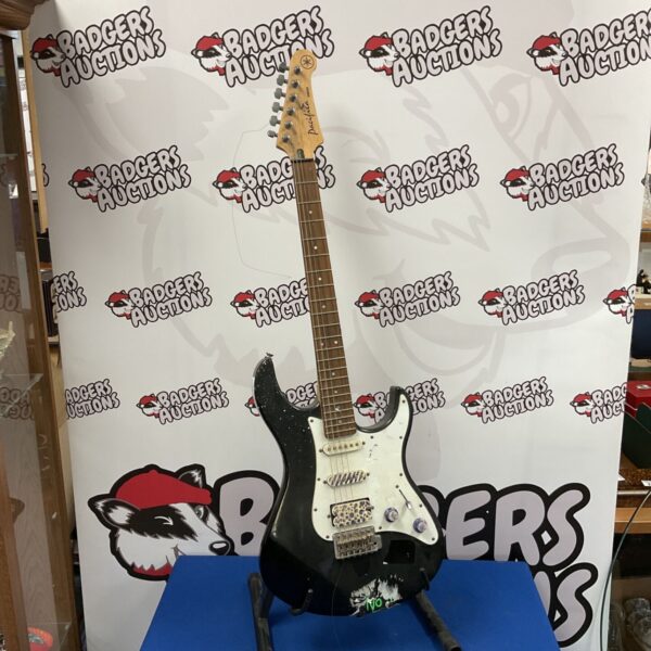Black Yamaha Pacifica electric guitar with white scratchplate on a stand