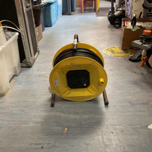 Yellow heavy-duty cable reel for workshop or construction site.